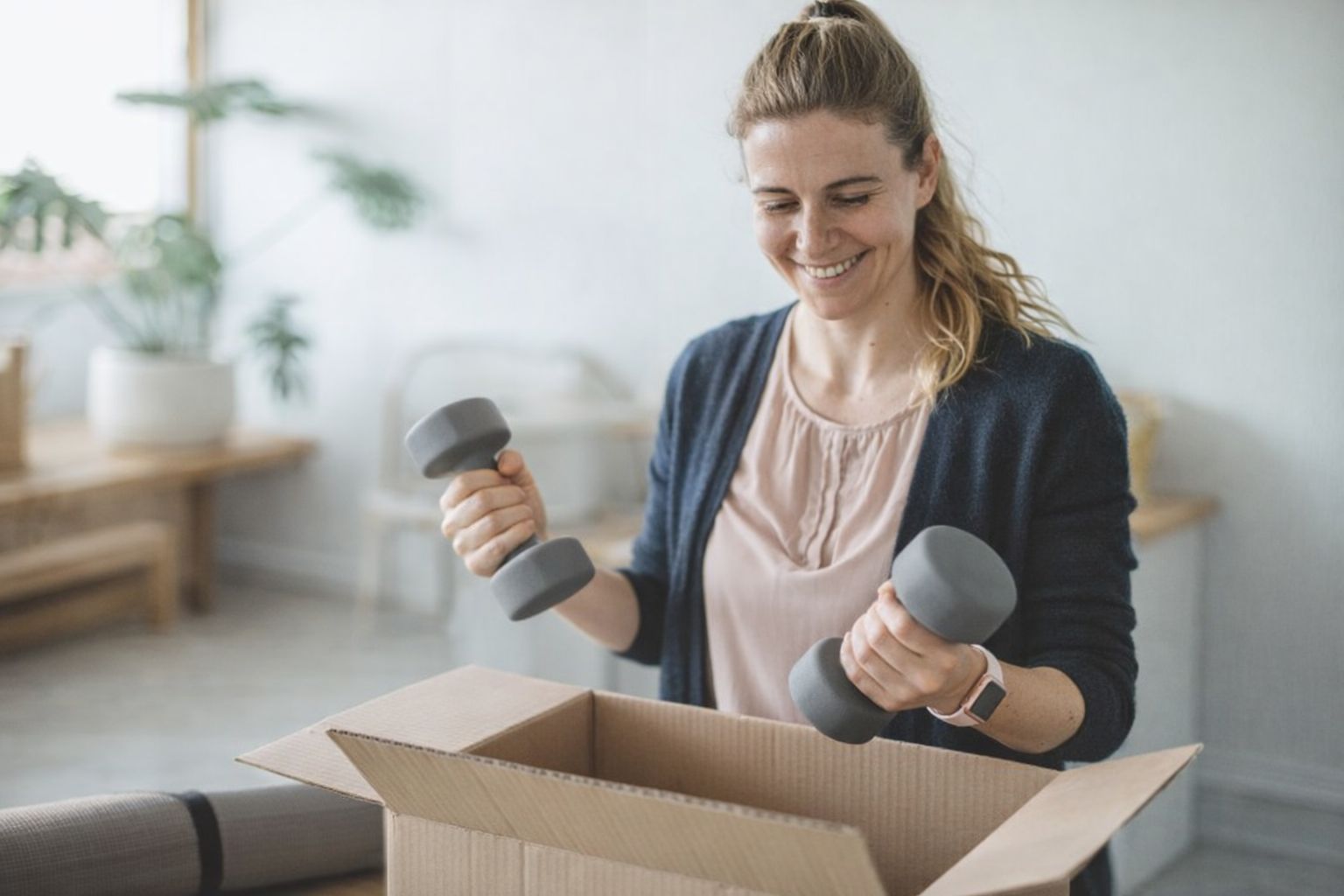 Frau packt Hanteln für den Versand in einen Karton.