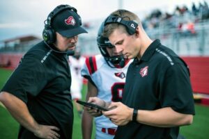 Zwei Football-Trainer besprechen am Spielfeldrand eine Tablet-Aufnahme
